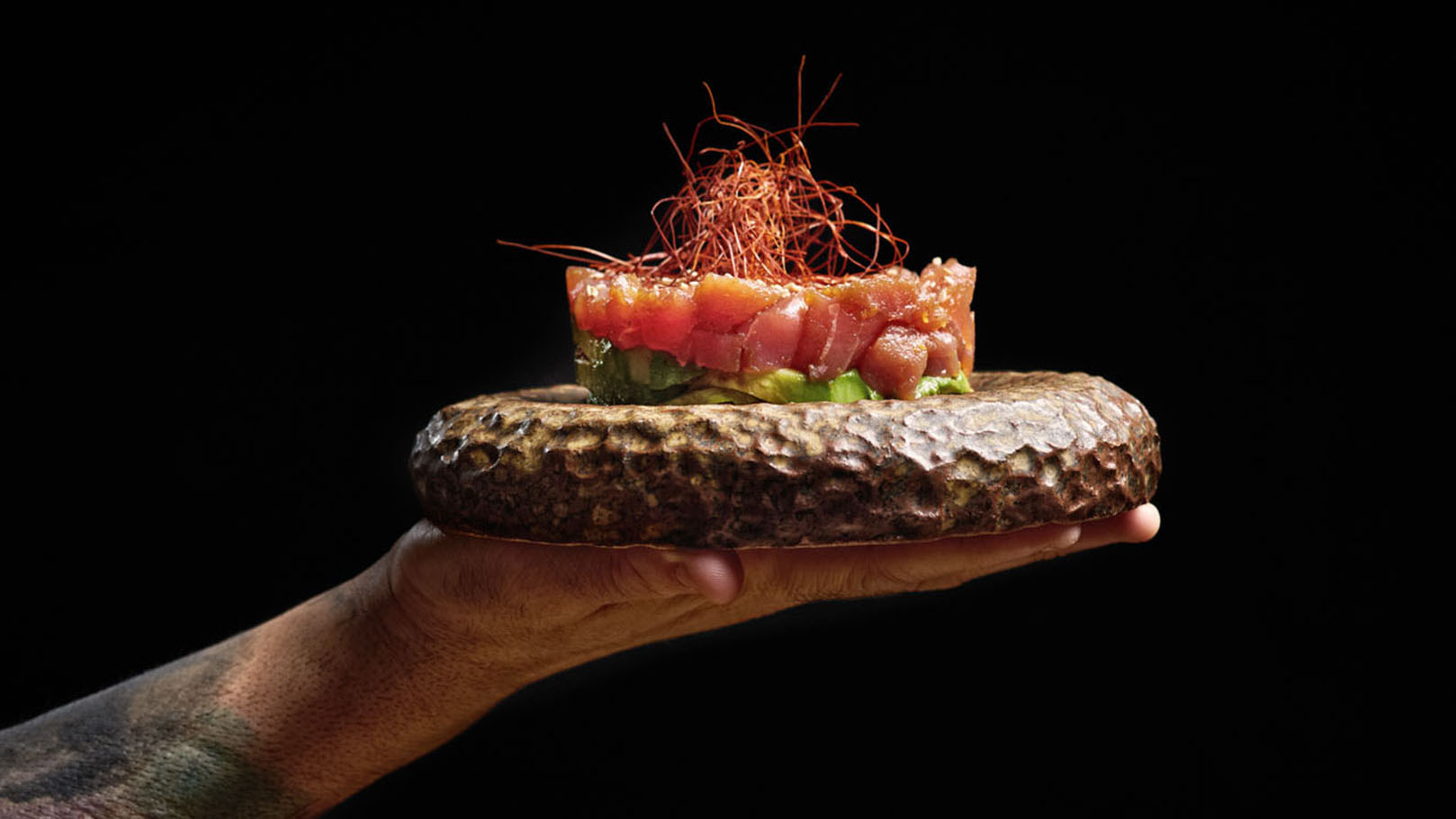 Mues.ca — A person is holding a plate with a piece of fish on it.