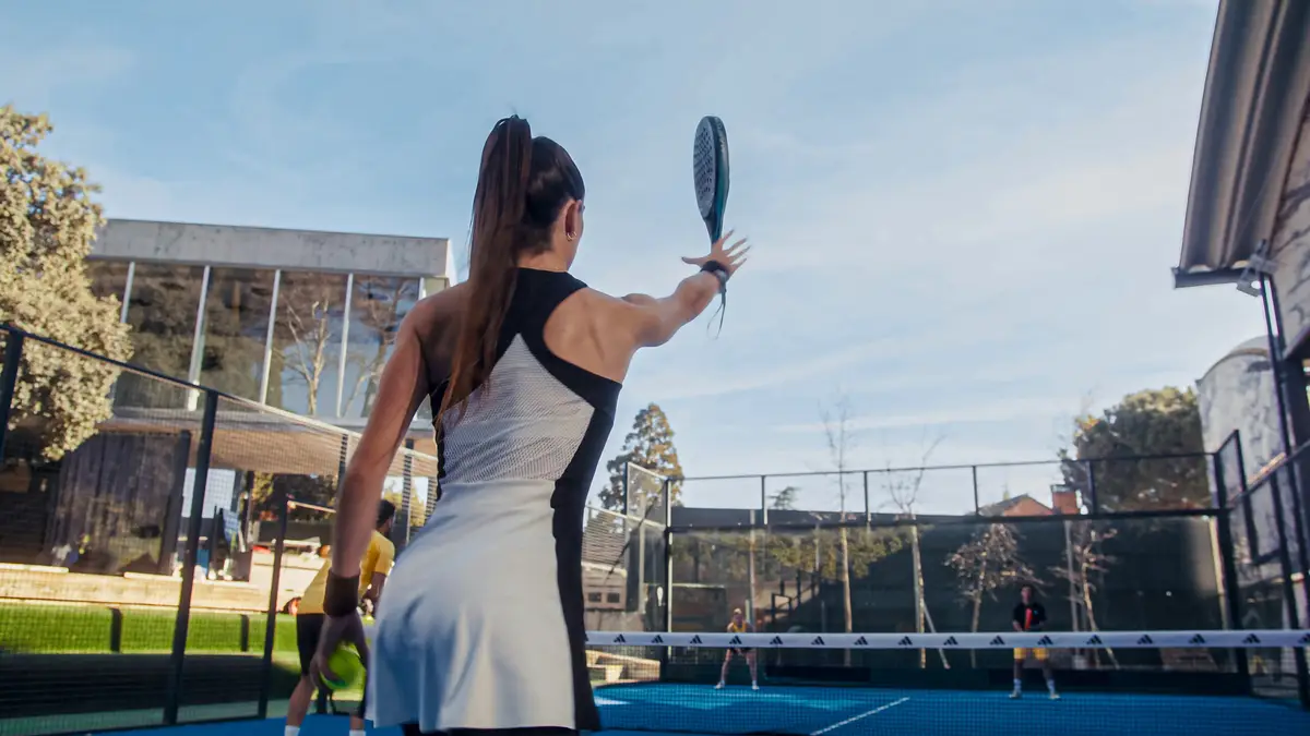 Adidas Crossit Thor — Una mujer con vestido blanco y negro juega al tenis.