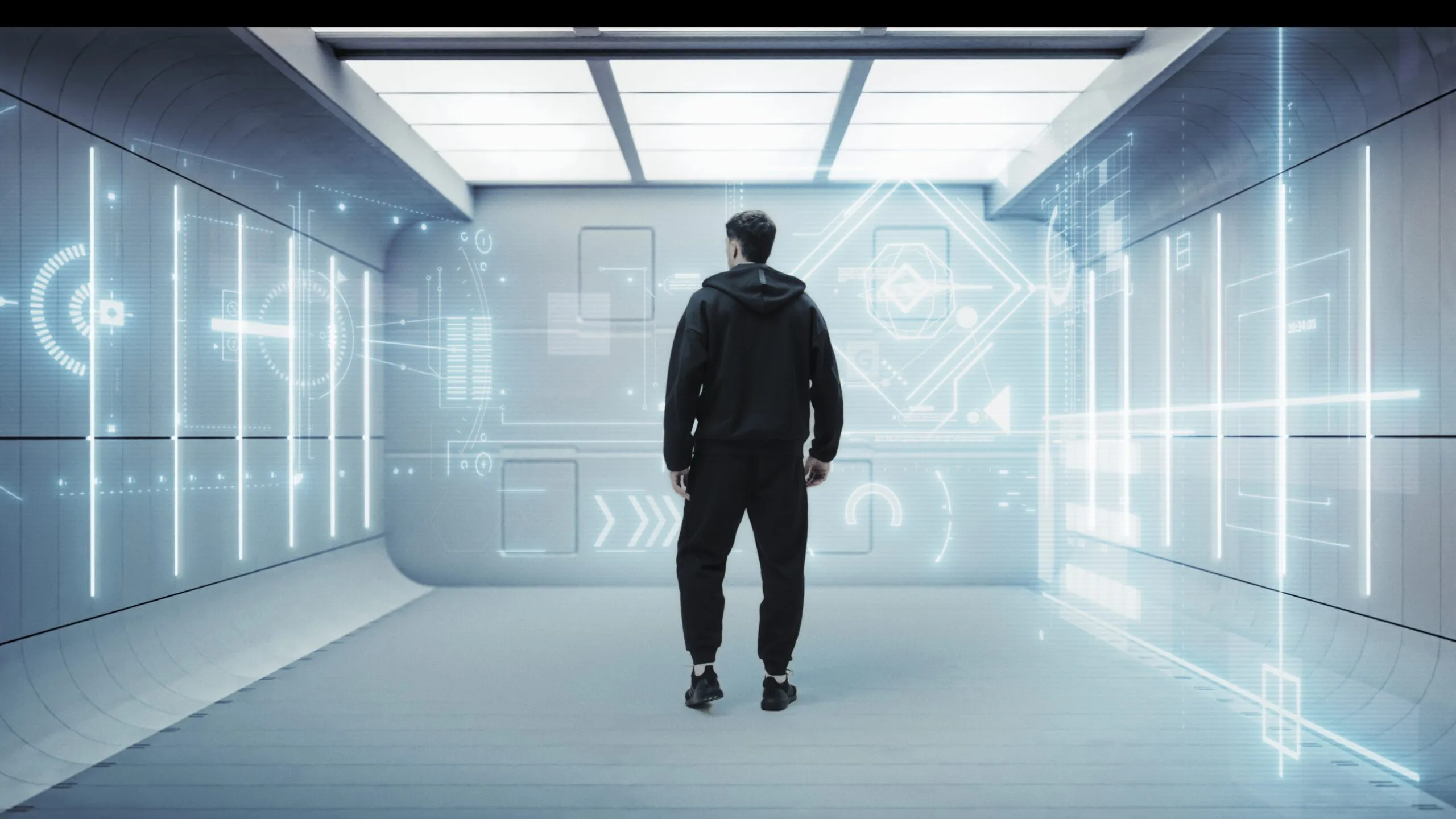 Adidas Metalbone 3.4 — A man wearing a black hoodie and black pants stands in a room with a blue background.