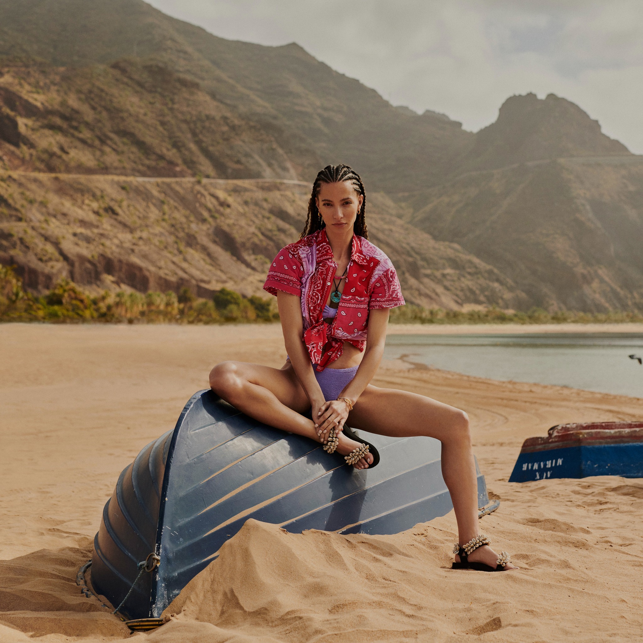 Harvey Nichols — A woman sits on a blue object on a beach.