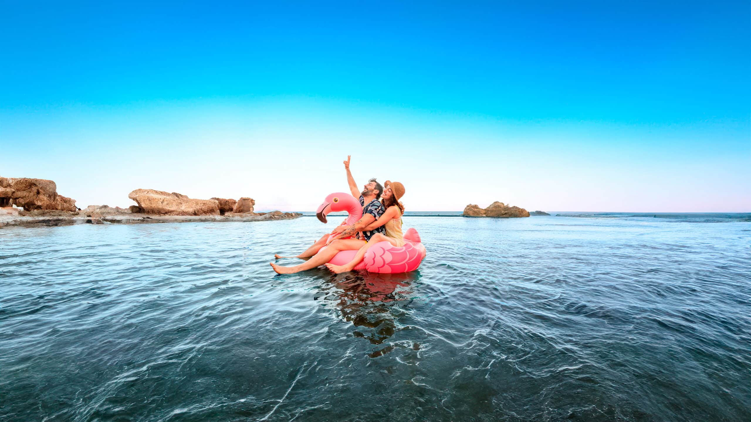IOC Clinica dental — Two people in a pink flamingo float on a lake.