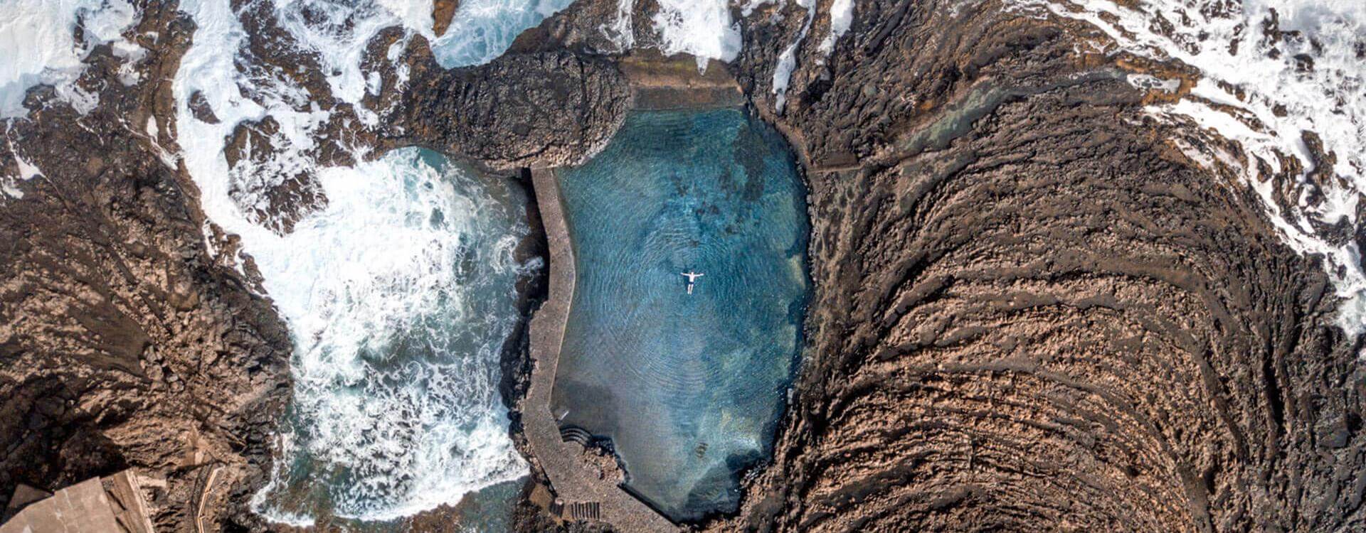 Isla con Alma — A blue pool of water with a rock wall and a white boat floating in it.