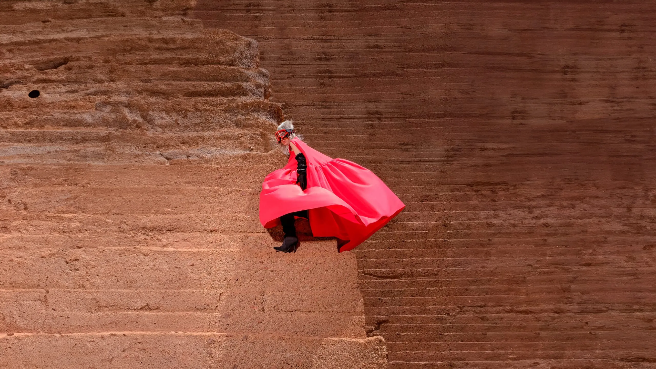 Lava Silhouttes — A person wearing a red cape and hat is flying through the air.