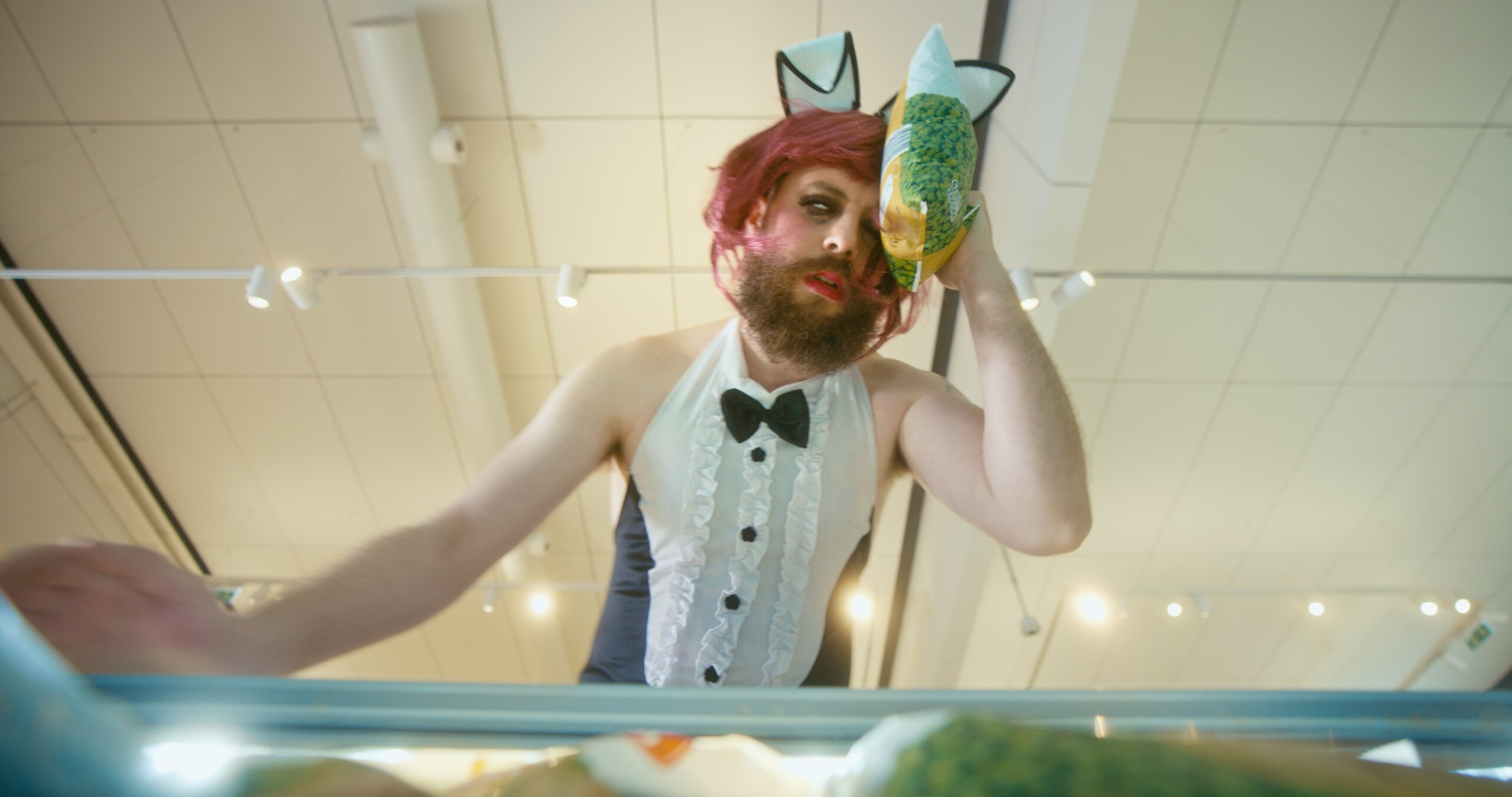 Lidl Carnaval 24 — A man with a beard and mustache wearing a white bow tie and a white dress with a cat on his head.