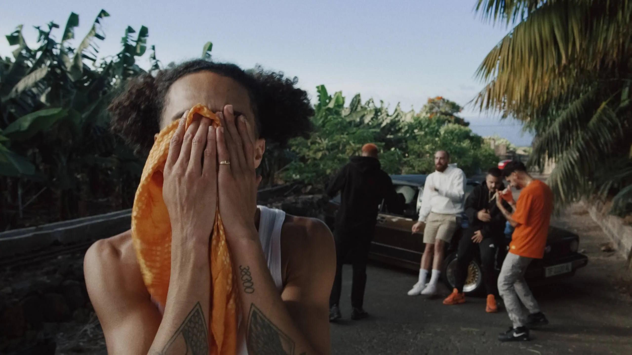 No le Bajes — A man with a towel over his face is standing in front of a group of people.