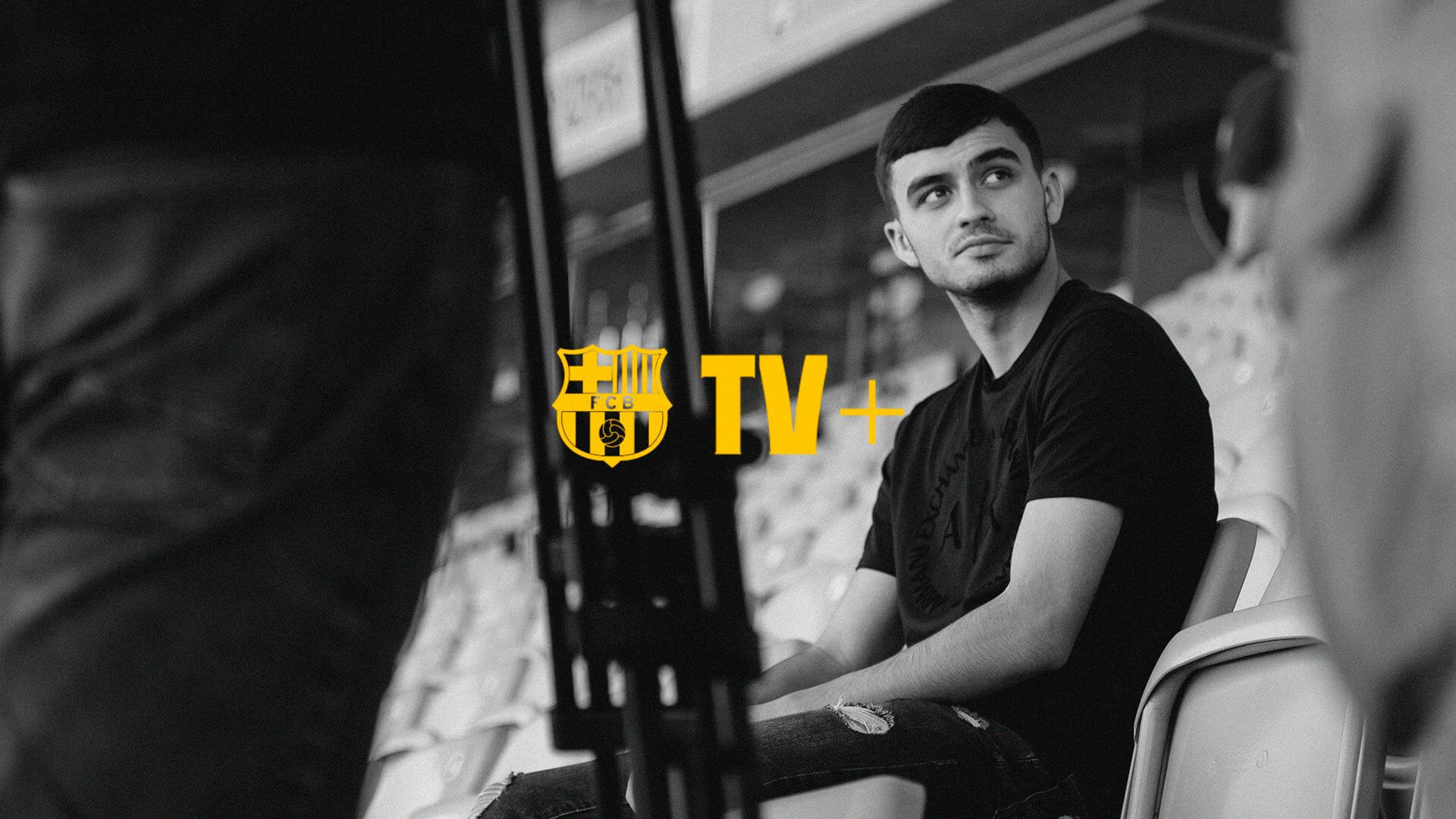Orígenes — A man wearing a black shirt and jeans sits in a stadium.