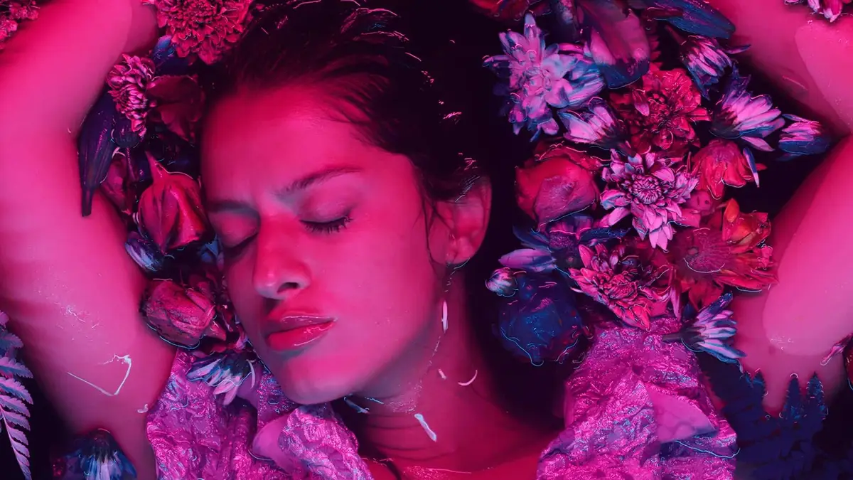 Valientes — Una mujer sobre fondo rosa con flores en el pelo.