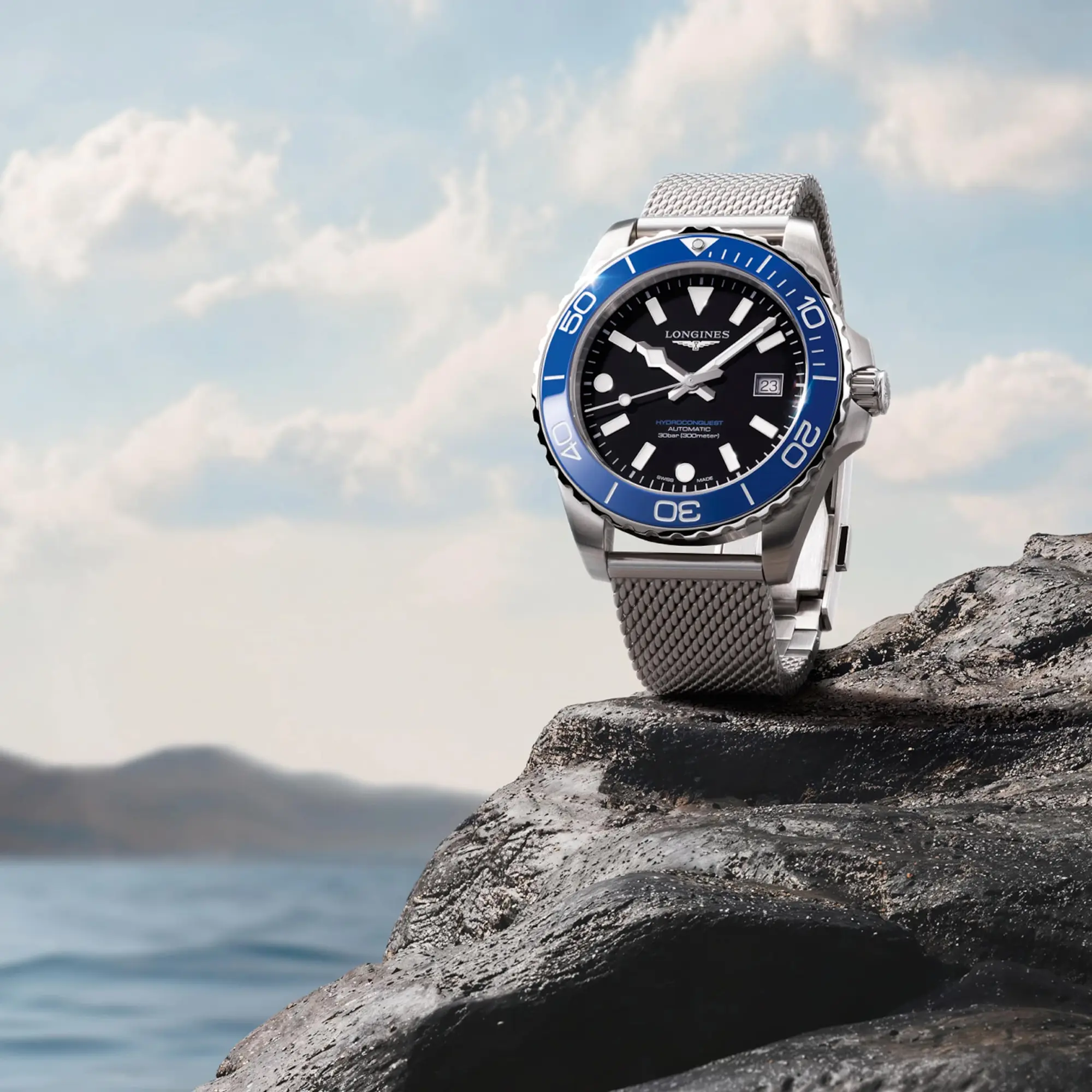 Longines HydroConquest — Longines — Longines HydroConquest watch with a blue bezel on a rock beside the sea.